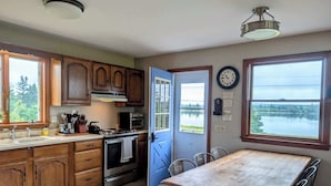 Une cuisine avec des meubles en bois, un fourneau et une vue sur un lac par la fenêtre.