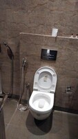 A bathroom with a toilet, a shower, and a towel rack.