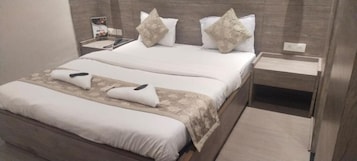 A hotel room with a double bed, a bedside table, a nightstand, and a wall-mounted telephone.