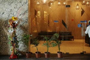 Un'area di accoglienza con una porta in vetro, un'elegante composizione floreale e diverse piante in vaso.