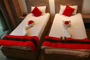 Two twin beds with red pillows, a red and black blanket, and a stuffed animal on each bed.
