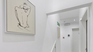 Un pasillo con piso de madera, paredes blancas y un boceto enmarcado en la pared.