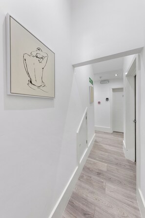 Ein Flur mit Holzboden, weißen Wänden und einer gerahmten Skizille an der Wand.