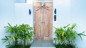 A wooden door with intricate carvings, flanked by two potted plants, and a sign indicating 'Villa Dita 01'. - Dita Villa Uluwatu (Uluwatu)