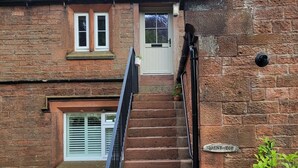 Une maison en briques avec un escalier menant à une porte, une petite fenêtre et une enseigne indiquant « BRENT TO ».