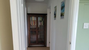 Un couloir doté d’un revêtement de sol en moquette, d’une bibliothèque en bois et d’une porte avec un interrupteur.