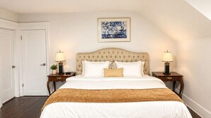 Een slaapkamer met een groot bed, twee nachtkastjes, een plafondlamp, een lijstwerk en een deur.