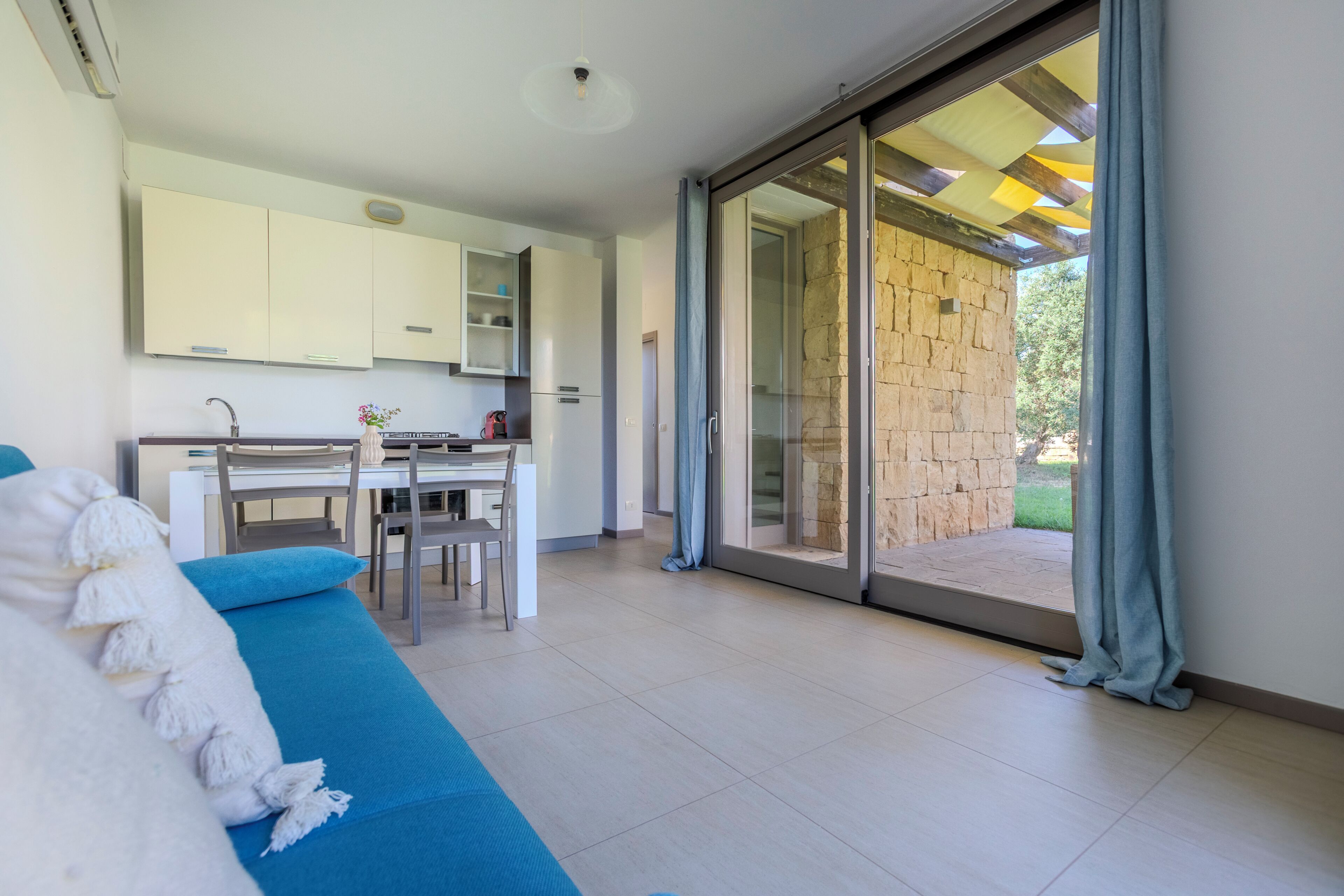 A modern interior with a dining area, a sofa, and a sliding glass door leading to an outdoor space.