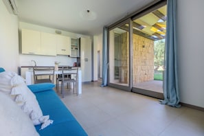 Un intérieur moderne comprenant un coin repas, un canapé et une porte-fenêtre coulissante donnant sur un espace extérieur.