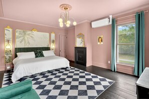 A bedroom with a large bed, a checkered rug, a fireplace, and a window with curtains. - FLX Victorian, Historical Charm + Modern Comfort, Perfect Location to Everything (Ovid)