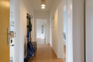 A hallway with a wooden floor, a coat rack, a table, and a door leading to another room. - Exciting Days in the Seaside City of Bremerhaven (Bremerhaven)