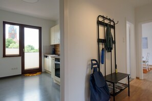 A modern kitchen with a built-in oven and a dining area with a bench and a coat rack.