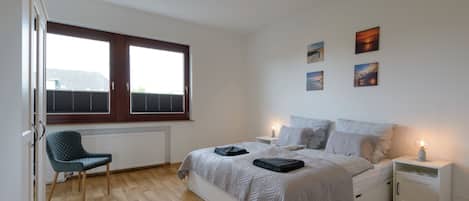 A bedroom with a bed, bedside tables, a chair, and artwork on the wall.