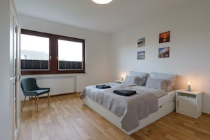 A bedroom with a bed, bedside tables, a chair, and artwork on the wall.