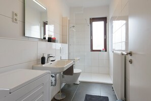 Et moderne badeværelse med hvid vask, spejl og toilet.