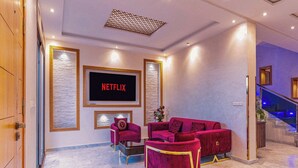 A modern living room with a large flat-screen TV, plush red sofas, and a marble floor. - Fabulous 3-bedroom house with AC in vibrant Marrakech (Marrakech)