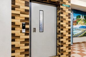 Hotellihuone, jossa on vastaanottotiski, hätäuloskäyntiä osoittava opaste ja seinällä suuri seinämaalaus.