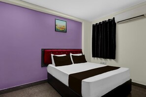 A hotel room with a bed, a headboard, a window with curtains, a wall-mounted picture, and a power outlet. - Hotel O Visakhapatnam Railway Junction (Visakhapatnam)