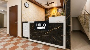 Un mostrador de recepción de hotel con un reloj, un ventilador de techo y un letrero que indica que es administrado por OYO.