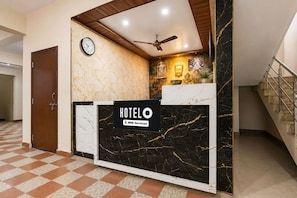 A hotel reception desk with a clock, a ceiling fan, and a sign indicating it is serviced by OYO. - Hotel O Visakhapatnam Railway Junction (Visakhapatnam)