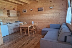Ein Holzblockhaus-Interieur mit Küchenzeile, Esstisch, Stühlen und einer Couch.
