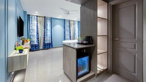 Habitación de hotel moderna con televisión de pantalla plana, minibar, refrigerador y puerta con manija.