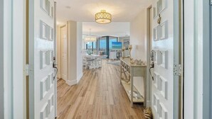 Un corridoio con pavimento in legno che conduce a una sala da pranzo con vista sull'oceano.