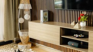A modern living room with a wooden TV stand, a floor lamp, and decorative items. - Cozy Lake View Haven (Kampala)
