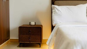 A bedroom with a bed, a nightstand with a cup, and a wooden wardrobe. - Cozy Lake View Haven (Kampala)