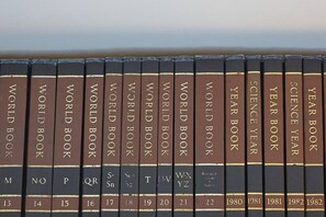 Une rangée de livres à couverture rigide intitulés « WORLD BOOK » et « YEAR BOOK », avec des étiquettes bien visibles sur le dos et les années de publication.