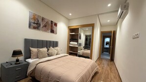 A bedroom with a bed, bedside table, lamp, artwork, wardrobe, mirror, and an air conditioning unit. - Elegant Stay - Les Acacias - Guéliz City Center (Marrakesh)