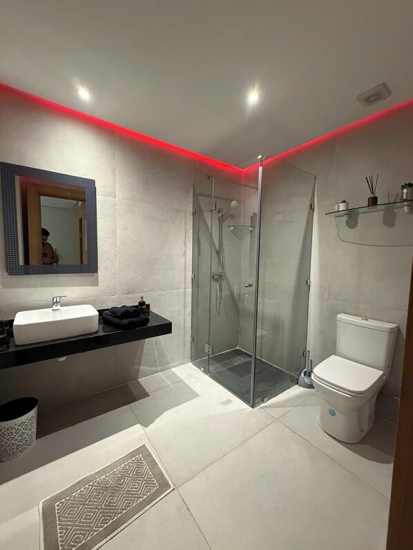 Ein modernes Badezimmer mit Duschkabine aus Glas, einem weißen Waschbecken und einer Toilette.