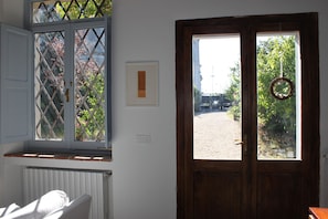 Ein Zimmer mit Holztür, einem Fenster mit Gittermuster und einem gerahmten Bild an der Wand.