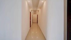 A narrow, well-lit hallway with a smooth floor, leading to a door at the end. - Classic Townhouse Nagawara Junction (Bengaluru)