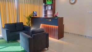 A reception area with a reception desk, two sofas, a small plant, and a wall-mounted clock. - Classic Townhouse Nagawara Junction (Bengaluru)