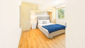 Un dormitorio con cama, mesitas de noche, un armario y una ventana.