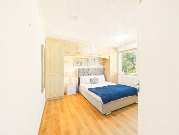 A bedroom with a bed, bedside tables, a wardrobe, and a window. - NEW! Oadby | 3-Bed Family Home with Parking (Oadby)