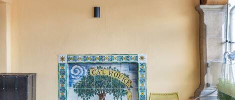 An outdoor patio with a tiled wall mural, wicker furniture, and a stone floor.