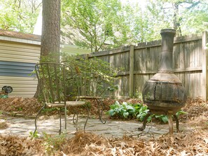 A patio area with a metal chair, a decorative metal planter, and a wooden fence. - Quiet Forest Hill/Restaurant/James River/Byrd Park (City of Richmond)