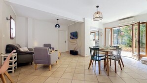 Een ruime woonkamer met een eettafel, stoelen, banken en een televisie.