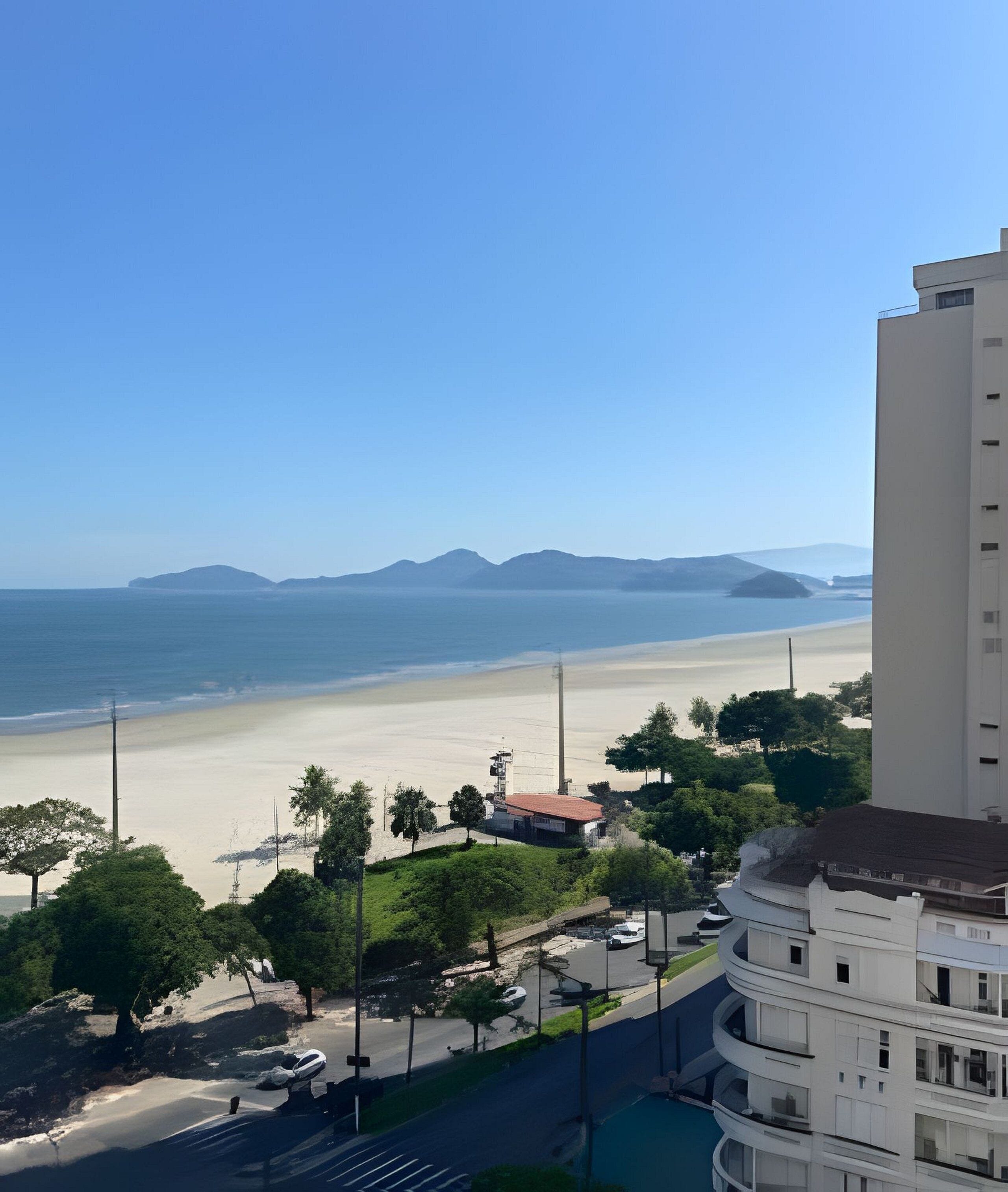 Vista costera con playa, una carretera y un edificio con balcones.