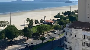A coastal view with a beach, a road, and a building with balconies. - SHB Piscina vista mar e pé na areia (Santos)