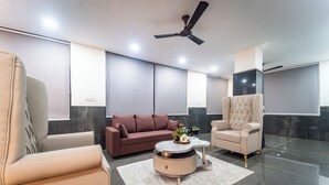A modern living room with a sofa, armchair, and round coffee table. - Zipp Lite Ballari Leela Hotel & Banquets (Ballari)
