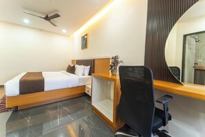 Une chambre d’hôtel avec un lit, un bureau, une chaise et un grand miroir.