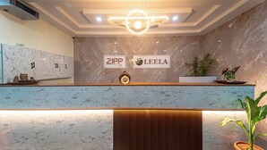 A hotel reception area with marble countertops, a modern light fixture, and a sign that reads 'ZIPP LITE.' - Zipp Lite Ballari Leela Hotel & Banquets (Ballari)
