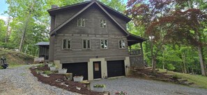 A two-story house with a garage, surrounded by a gravel driveway and potted plants. - Cozy Cabin- Pisgah Forest, Trails, Waterfalls, River, Brevard & Asheville (Mills River)