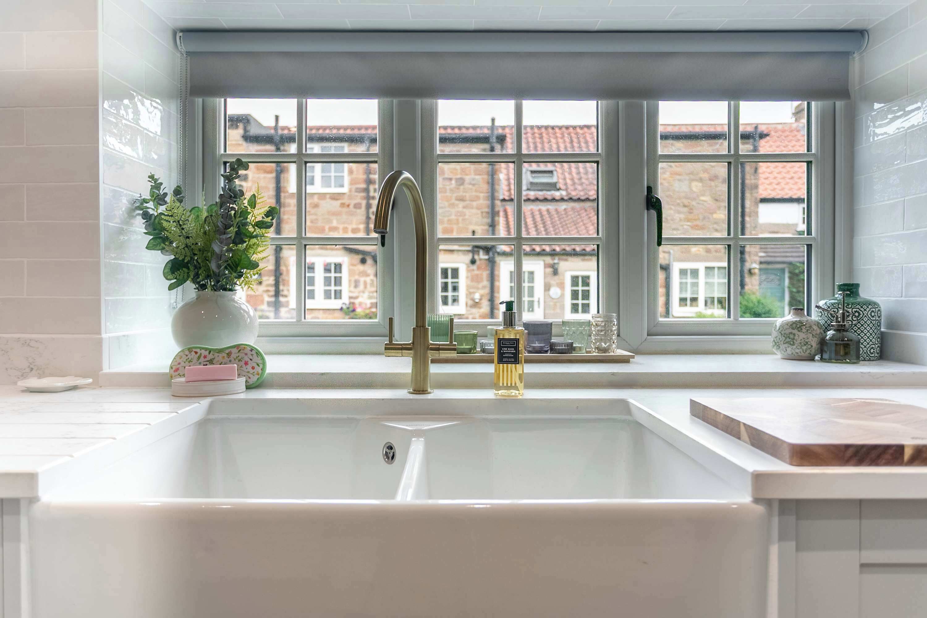 A kitchen with a large window, a sink, and a plant on the windowsill.