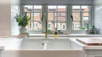 A kitchen with a large window, a sink, and a plant on the windowsill.