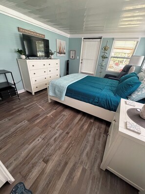 A bedroom with a bed, dresser, television, and a window with blinds. - Peaceful room with kitchenette in peaceful Homosassa w/boat parking on premises. (Homosassa)