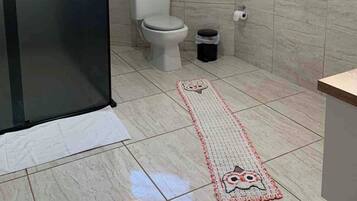 Un baño con inodoro, cubo de basura, ventana y puerta.